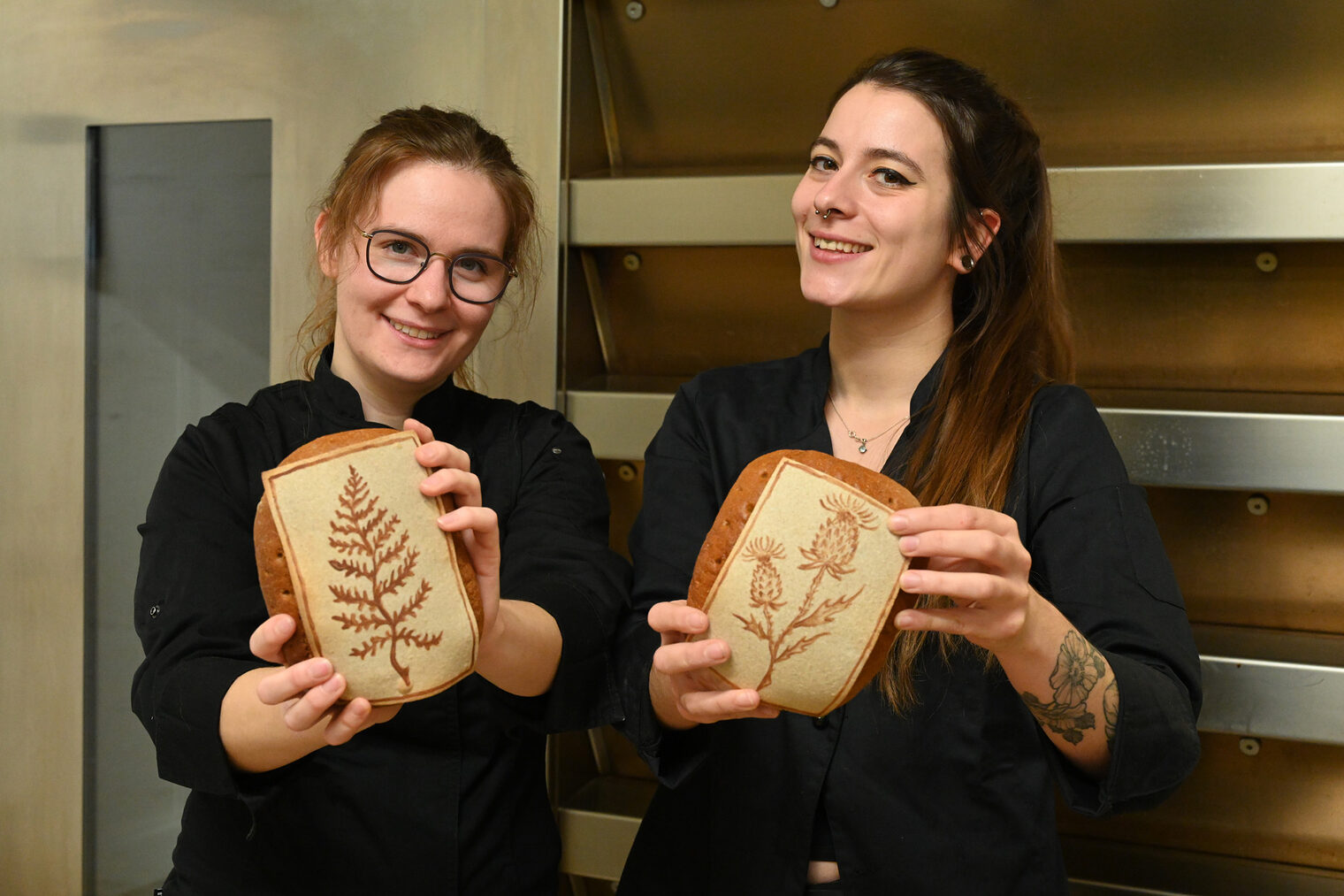 Bäckerinnen halten beide ein Brot in die Kamera
