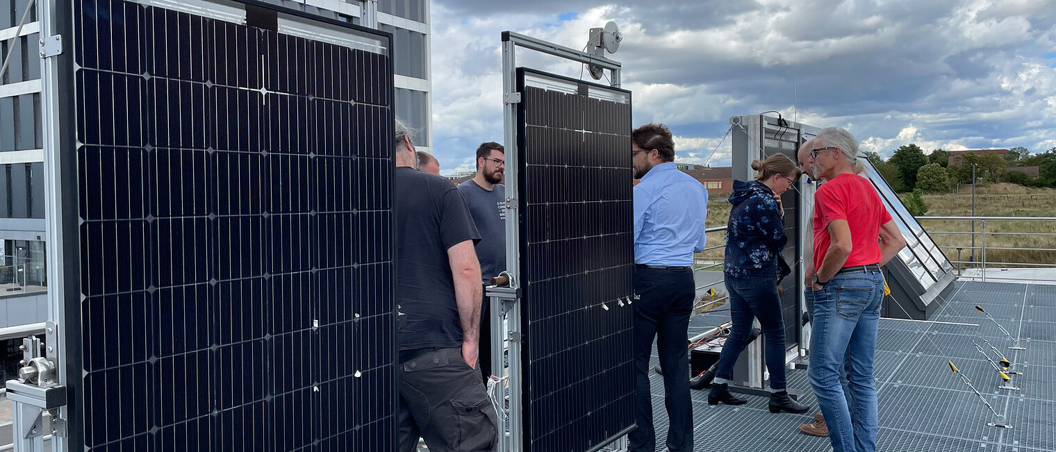 Gruppe auf Dach schaut sich Solarmodule an