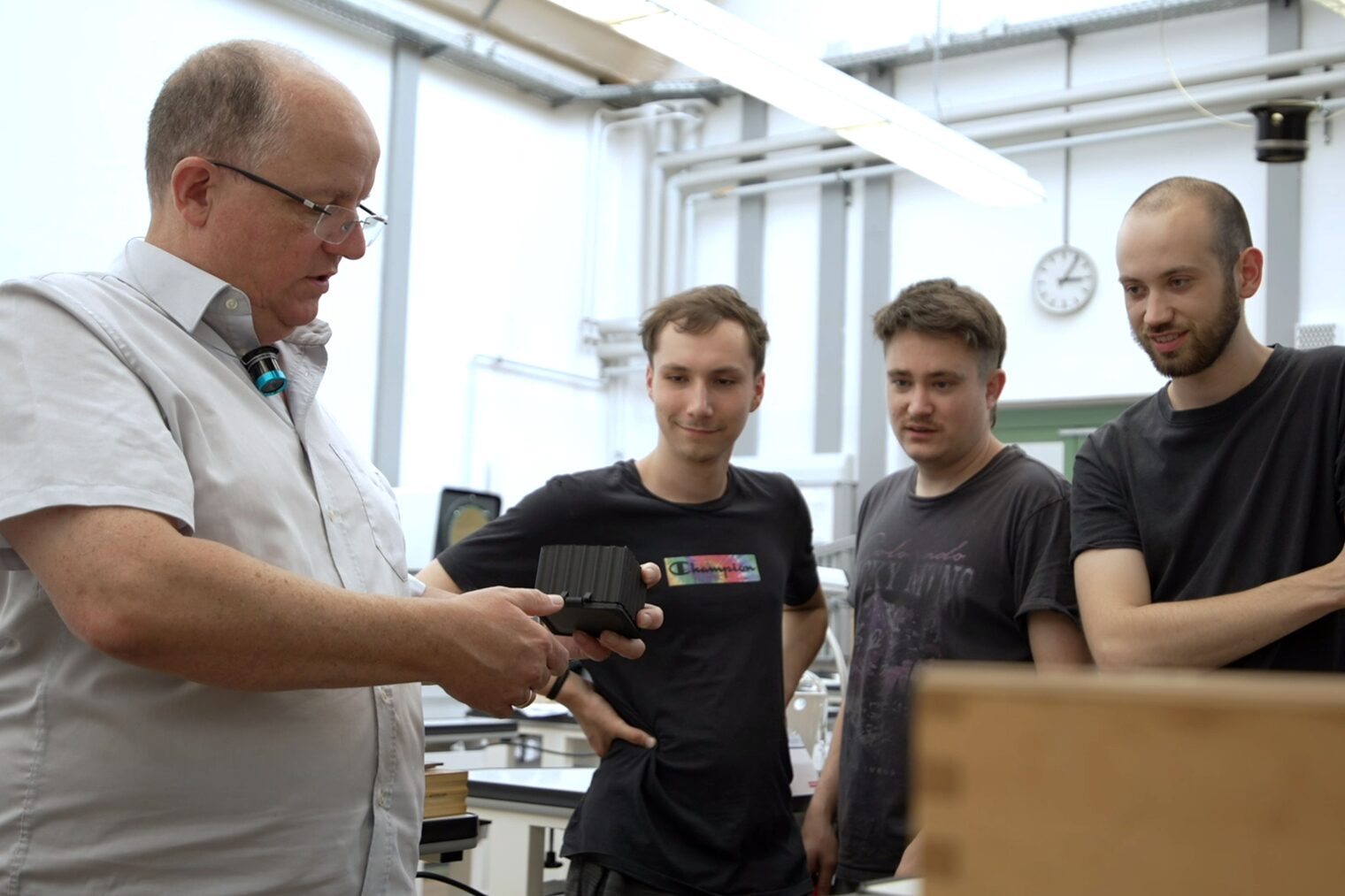 Der Kursleiter des Uhrmachermeisterkurses, Herr Eberlein, erklärt etwas seinen Meisterschülern.