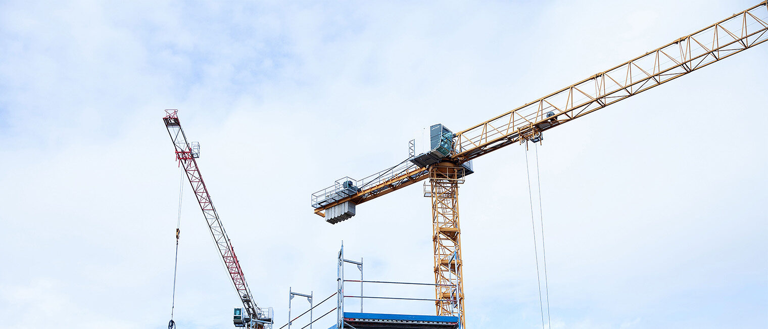 Trotz gesamtwirtschaftlich schwieriger Rahmenbedingungen präsentierte sich die Konjunktur im unterfränkischen Handwerk 2024 stabil. Insgesamt 83,5 % der Betriebe bezeichneten ihre Geschäftslage als gut oder befriedigend. Kran vor blauem, leicht bewölktem Himmel