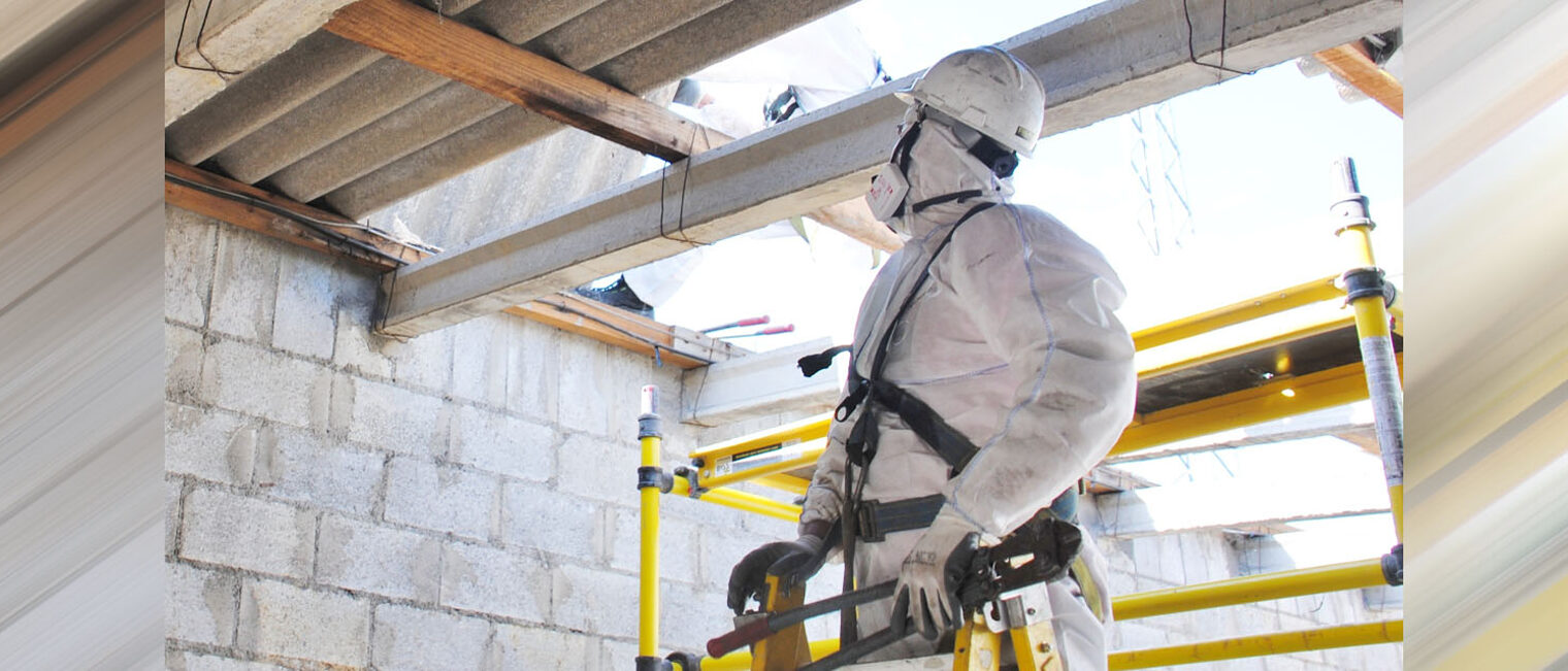 Bauarbeiter in Schutzanzug auf Baustelle vor Asbestplatten