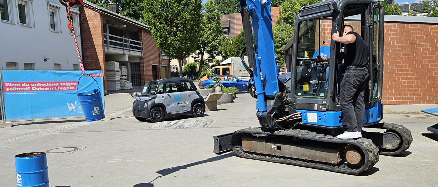 Blauer Bagger auf Pflastersteinen im Hof der Bauinnung Schweinfurt