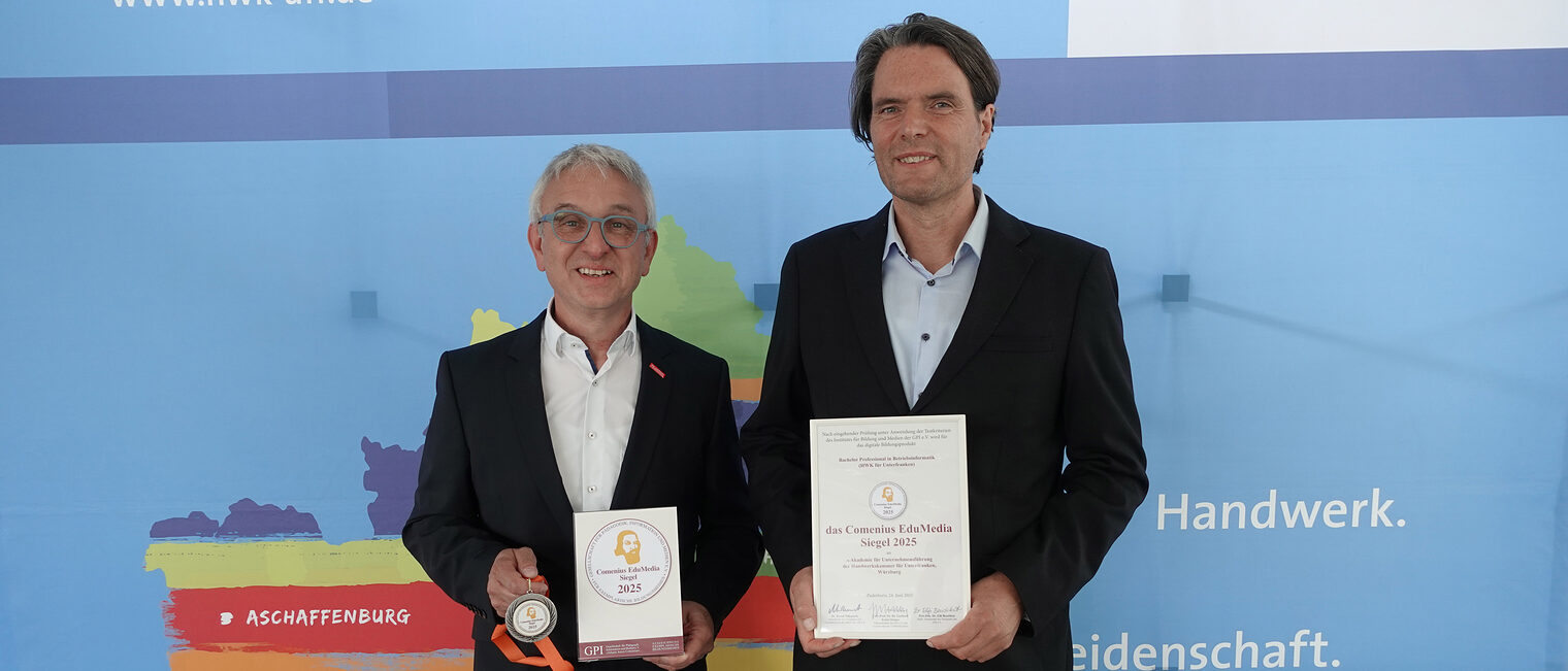 Zwei männliche Personen halten Urkunde in der Hand