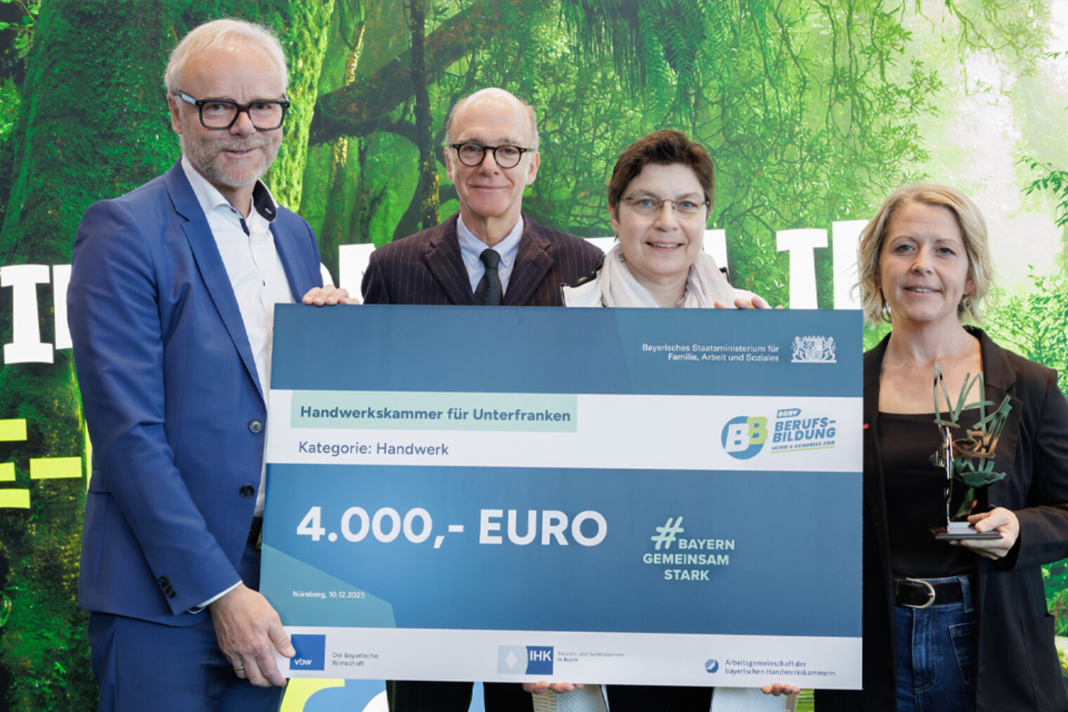 Gruppenfoto vier Personen mit Gewinnscheck, Aufschrift: 4.000 Euro