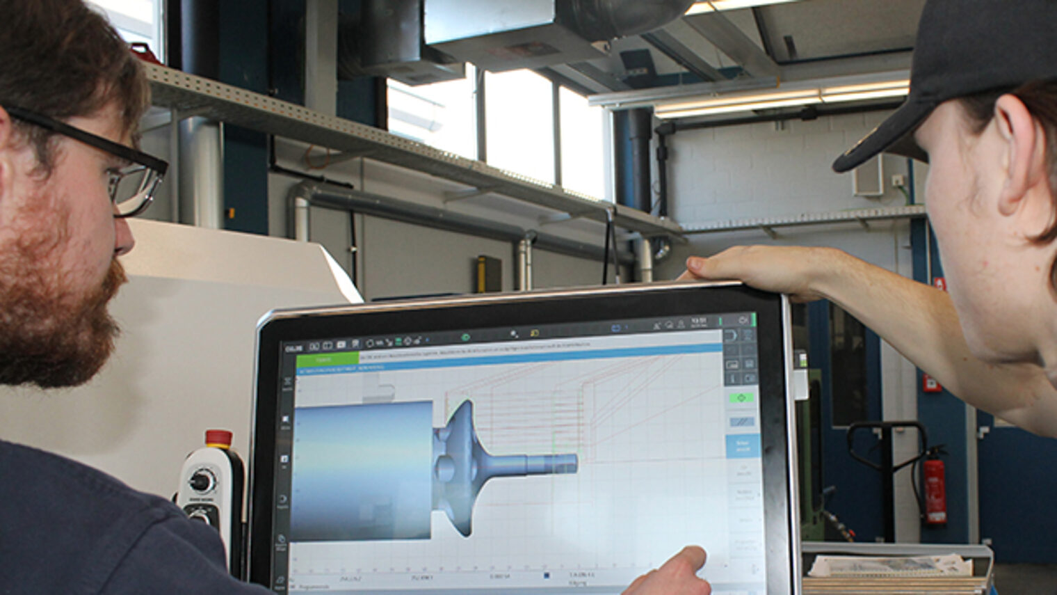 Lehrmeister betreut Schüler beim Bedienen der Drehmaschine in der ÜLU Feinwerkmechanik im Bildungszentrum Aschaffenburg