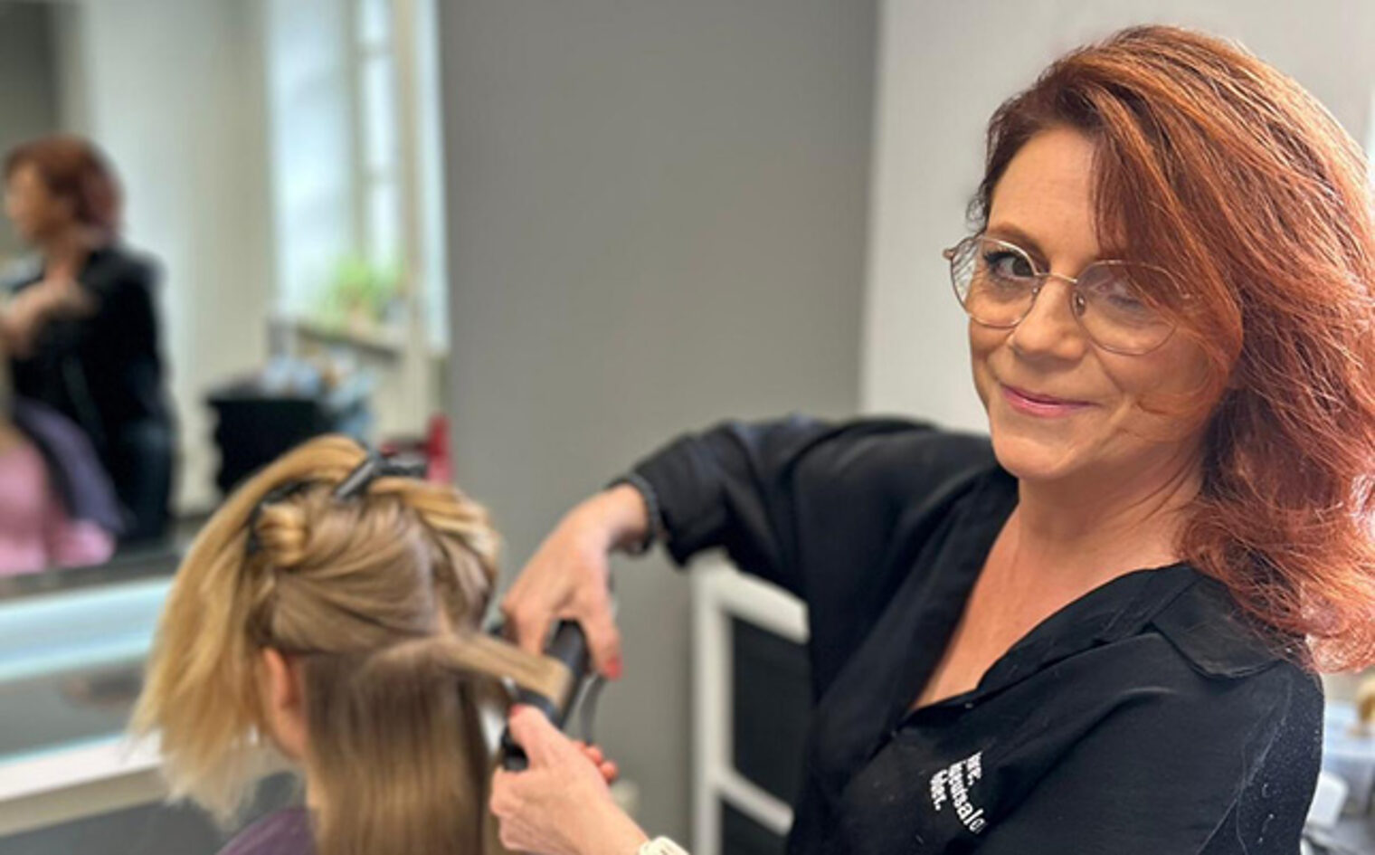 Antonia Röder, Friseurmeisterin & Dozentin an der HWK, stylt eine Hochsteckfrisur mit Lockenstab im Salon