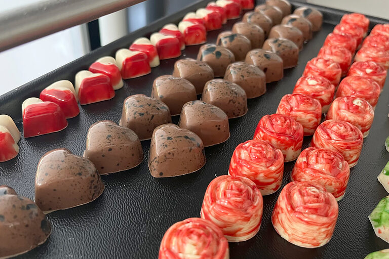 Vielfältige Pralinenkreationen hergestellt aus Formen oder handwerklich gespritzt, überzogen und dekorativ verziert.